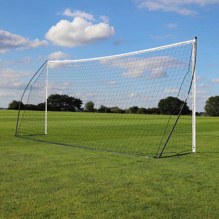 KICKSTER draagbaar voetbaldoel 500 x 200 cm laag van opzij op het gras, met het zwarte achterframe en het net.