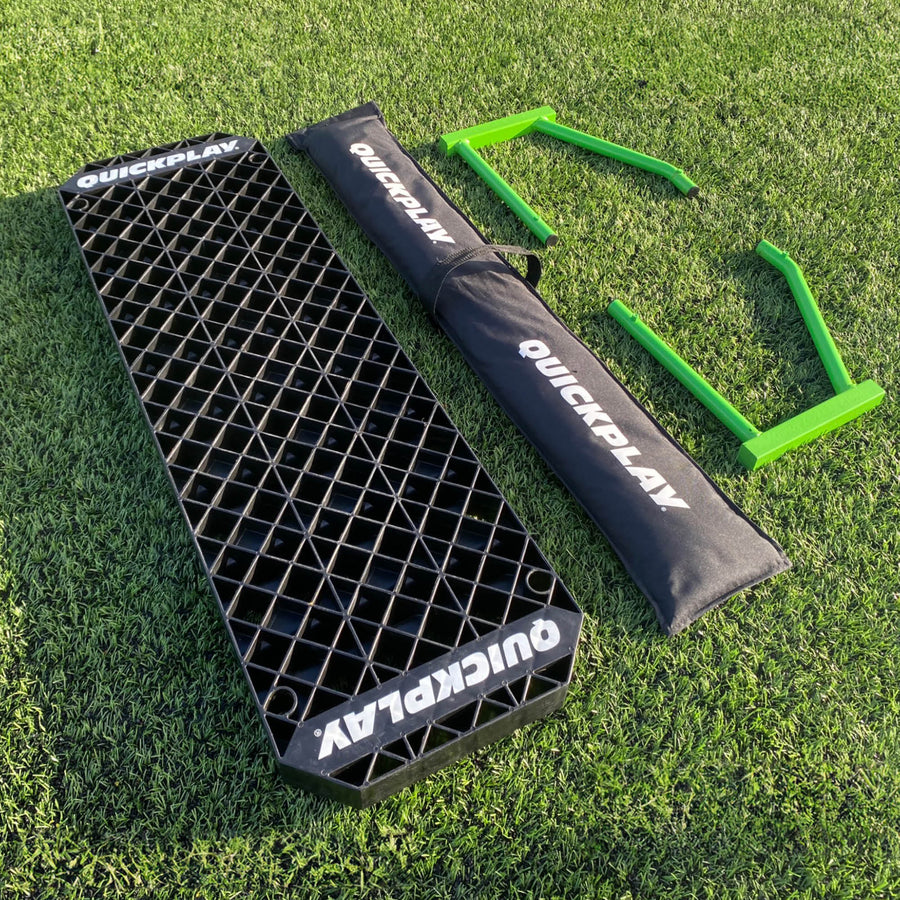 Onderdelen van de REPLAY Station XL op het gras: zwart bord, zwarte QUICKPLAY tas en twee groene frames.