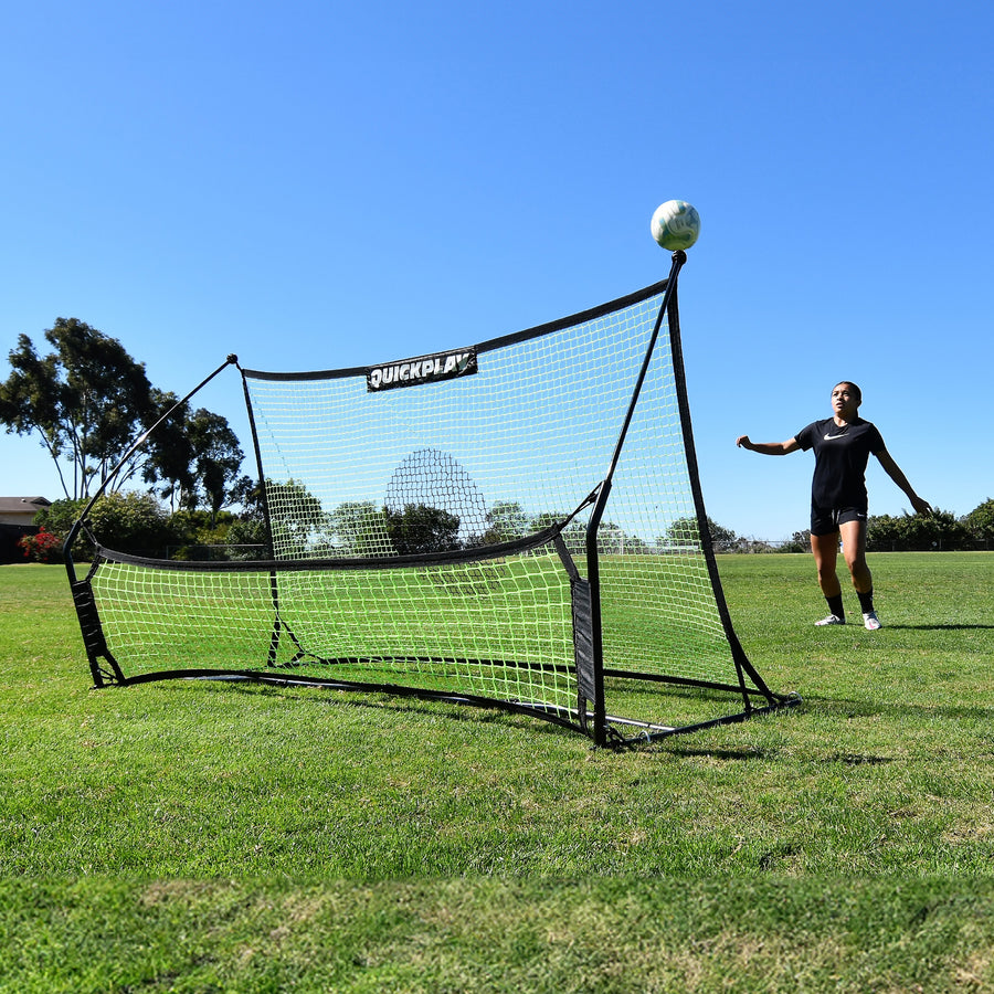 Speler wacht op een bal die omhoog kaatst van de TEKKERS Trainer voetbalrebounder met dubbel net op een grasveld.