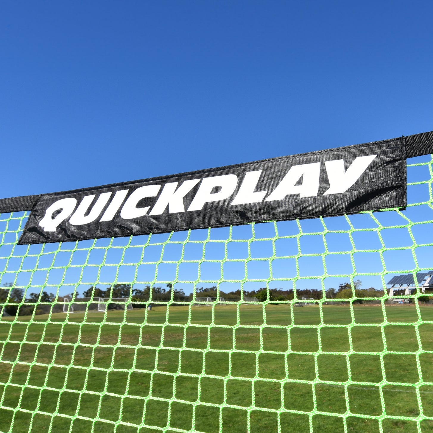 Close-up van de zwarte QUICKPLAY banner langs de bovenkant van het groene net van de TEKKERS Trainer.