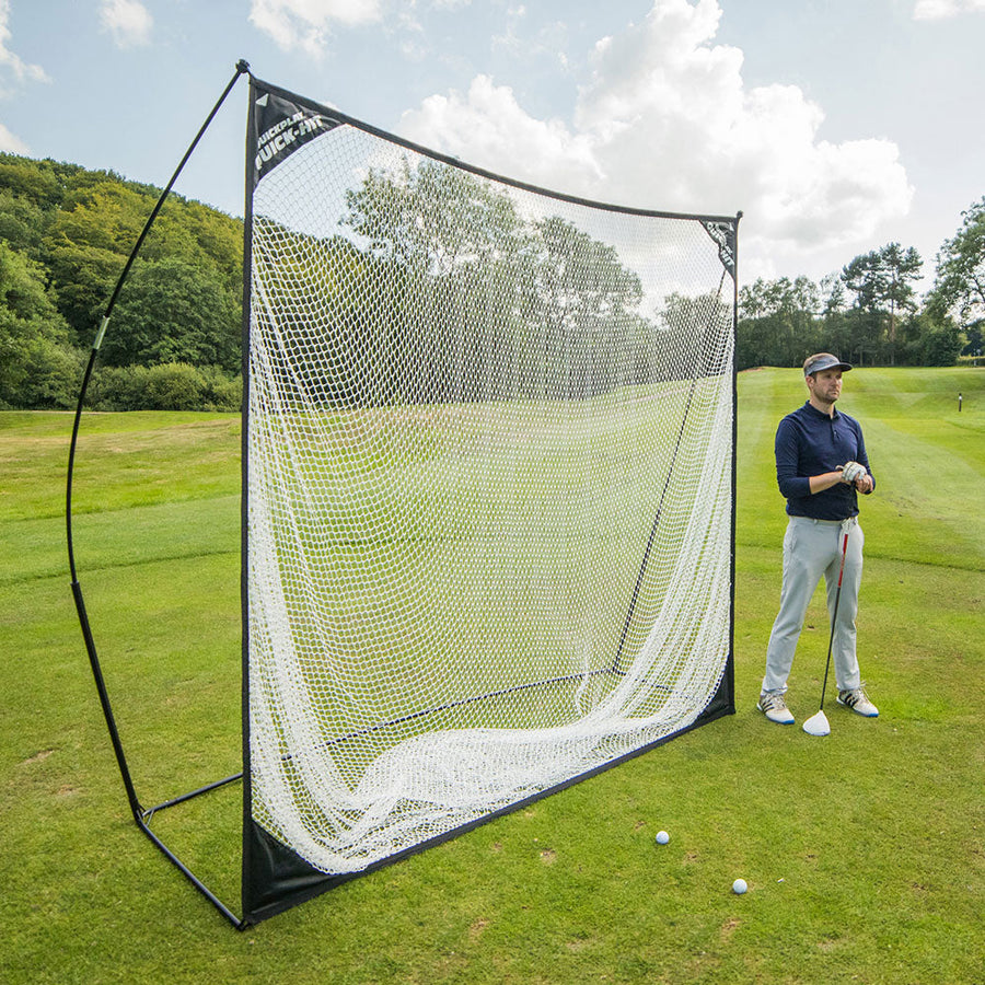 QUICK-HIT golfnet 240 x 240 cm opgezet op een golfbaan, met een golfer met een club ernaast en ballen op het gras.